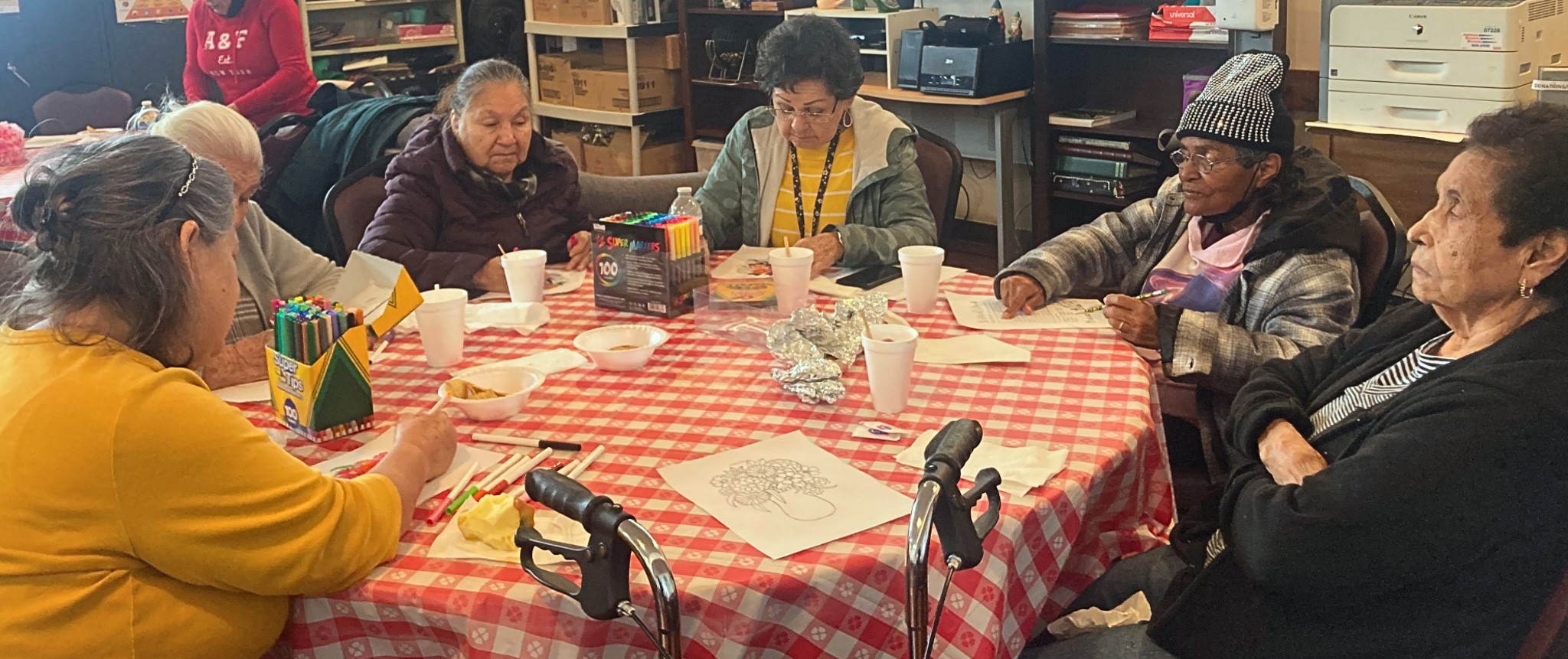 Older adults sitting around a table enjoying coloring activities